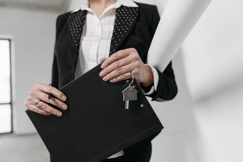 Fully Managed Letting Service vs Let-Only Service: Which One Should You Choose? 1 Close-up of a realtor holding a keychain and clipboard with interior office background.